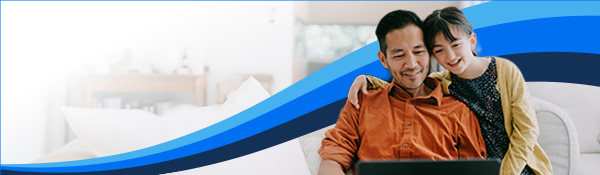 Smiling father works on a laptop while his young child hugs him